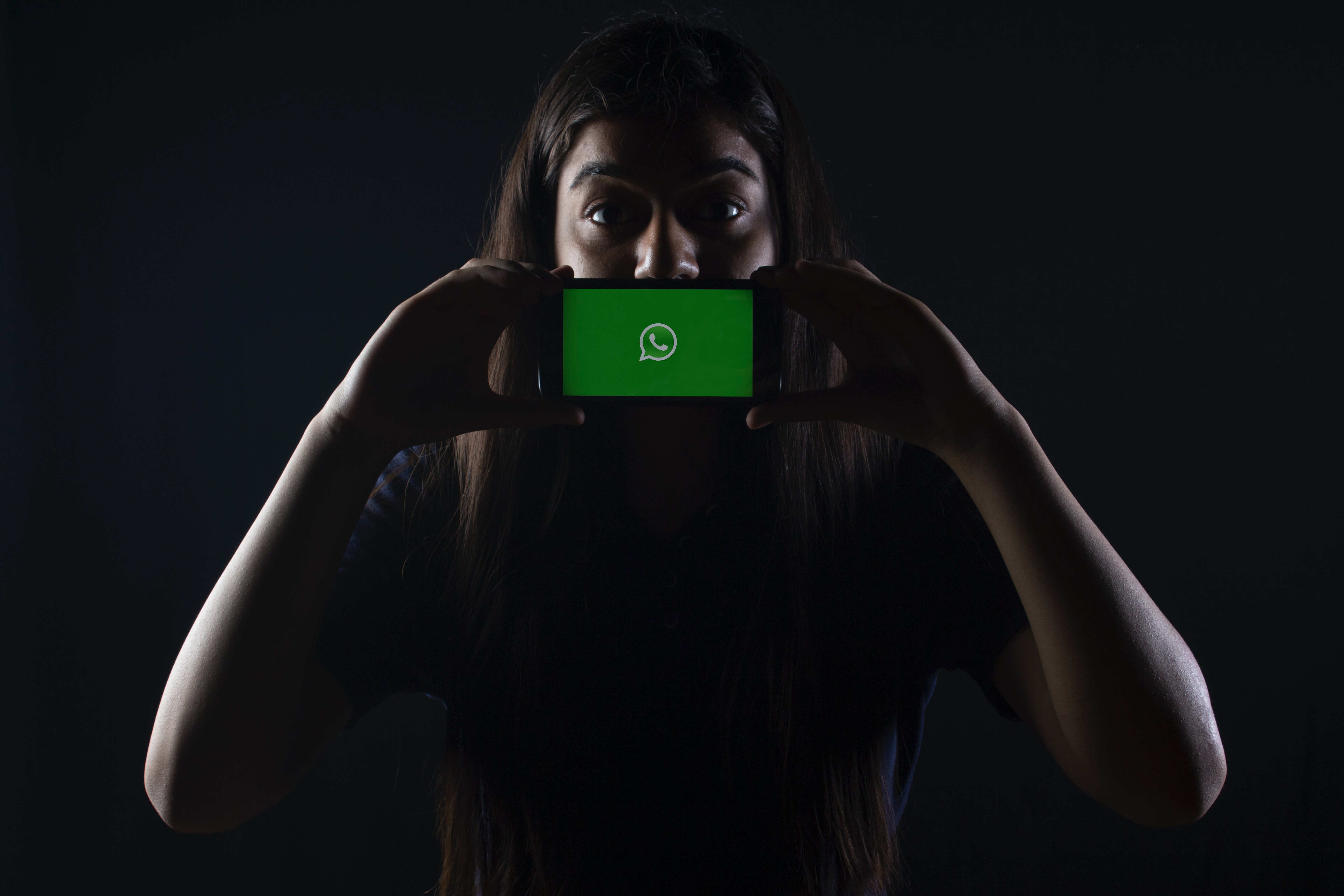 Woman holding black smartphone with whatsapp logo